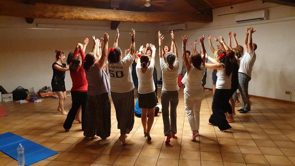 sessione di yoga della risata persone in cerchio con le mani alzate ridono